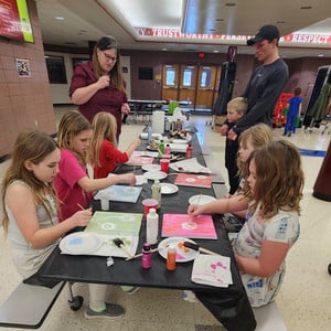 Students using paint to create dandelion designs on paper